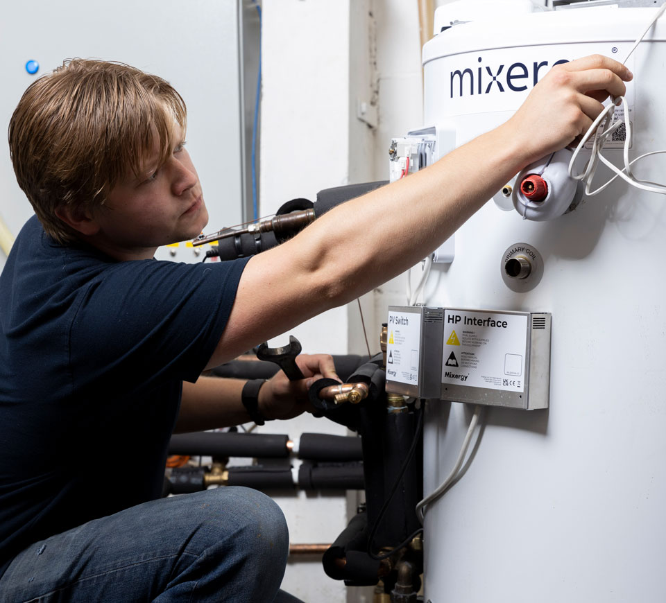 A man installing a Mixergy smart hot water cylinder