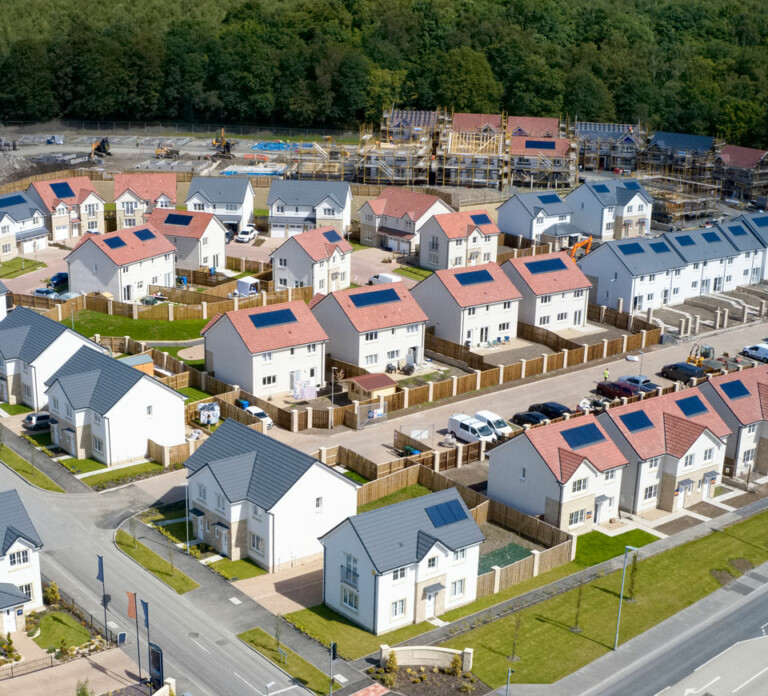 An aerial view of a new build housing estate with solar panels